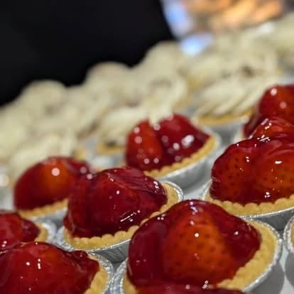 Small strawberry tarts in foil cases, topped with glazed strawberries.