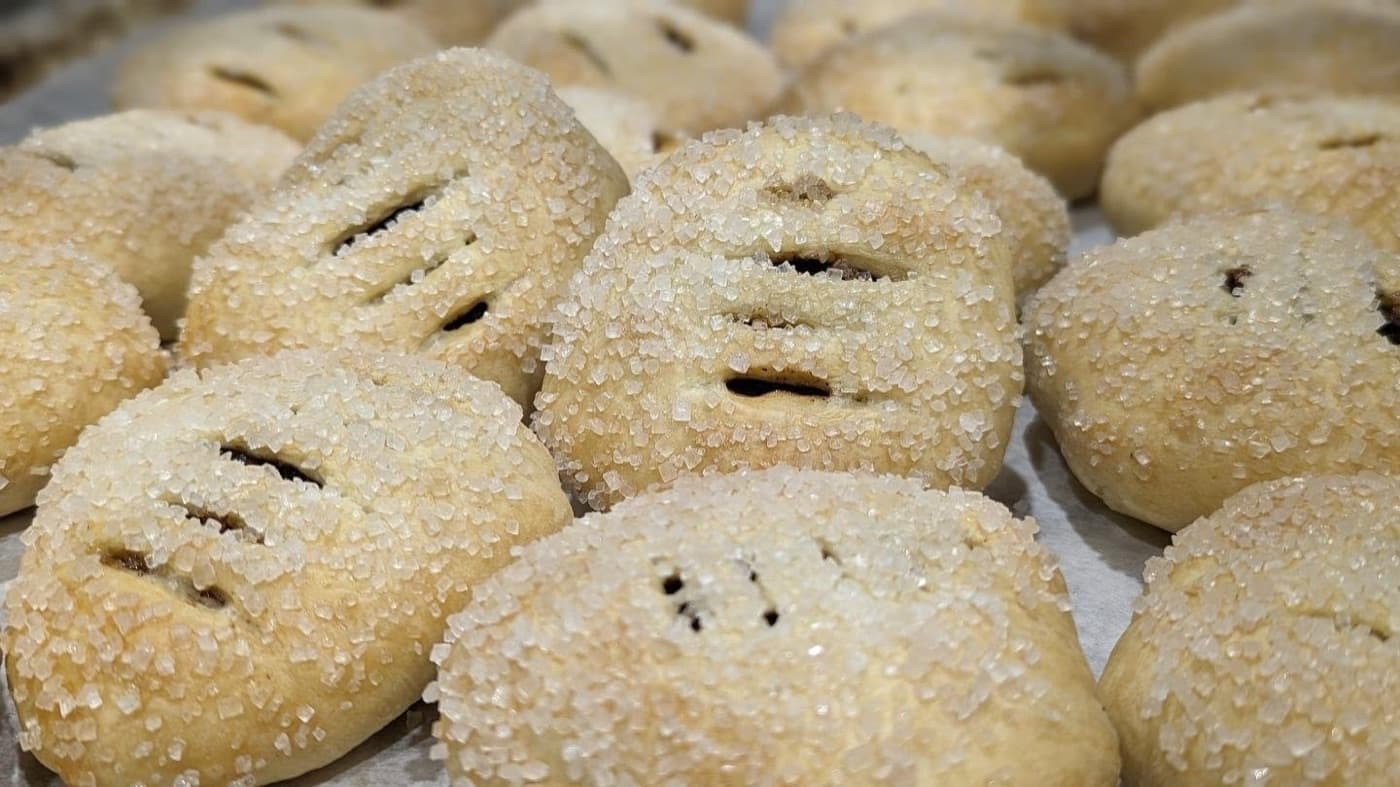 Two round golden Eccles cakes with flaky pastry and visible currants showing through.