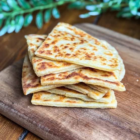Golden pan-fried Scottish potato scones stacked on a plate as part of a full cooked breakfast.