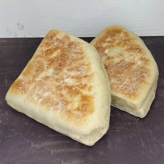 A triangular Irish soda scone farl split and lightly fried, served warm with butter on a plate.