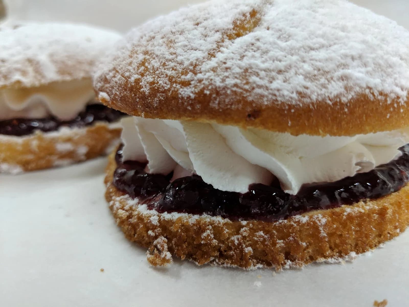 Mini Victoria sponge cakes filled with jam and piped cream, dusted with icing sugar.