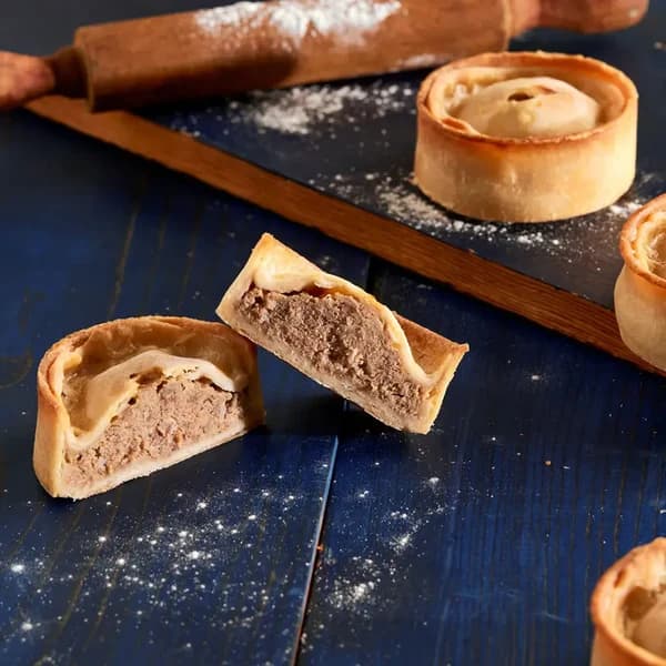 A round double-crust Scotch pie in firm golden pastry with a dished, filling-ready top, sitting on a plate.