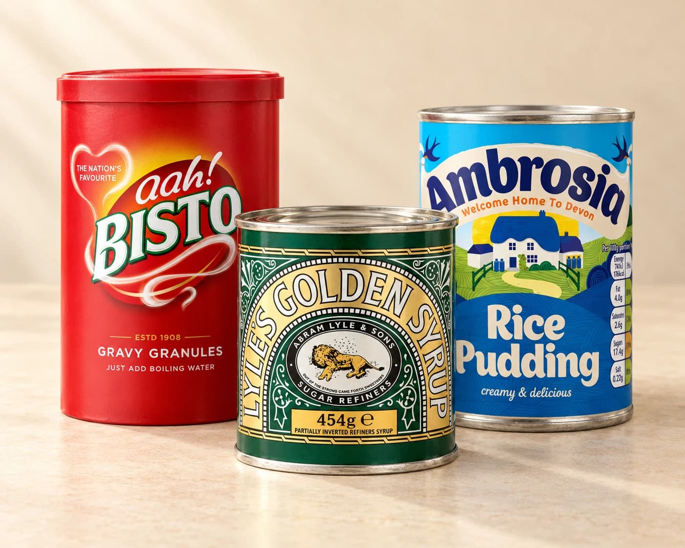 A Bisto gravy granules tub, Lyle’s Golden Syrup tin and Ambrosia Rice Pudding tin on a cream tabletop.