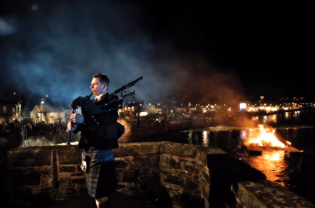 A piper in full Highland dress playing at a Burns Night celebration